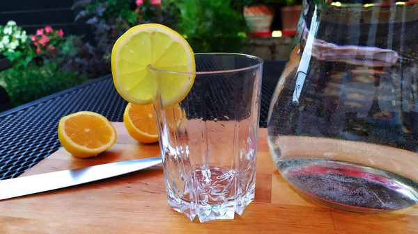 Doldurulmaya hazır limonla süslenmiş boş bir bardağın manzarası, arka planda tahtadan bir limonun iki yarısı, fotoğraf.