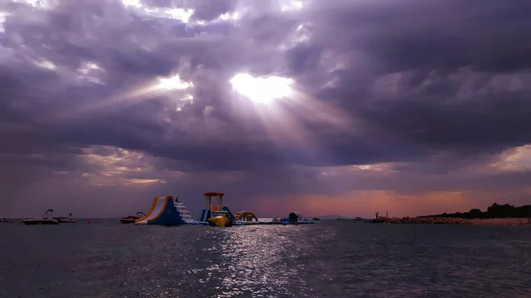 Çocukların oynadığı denizin üzerinde kauçuk bir şatonun üzerinde gün batımını izlemek, fotoğraf.