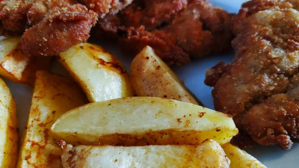 Yakından bakınca fırında patates ve kızarmış domuz pirzolası servis etmeye hazır yemek, iyi bir tat, patateslere yakın çekim, fotoğraf.