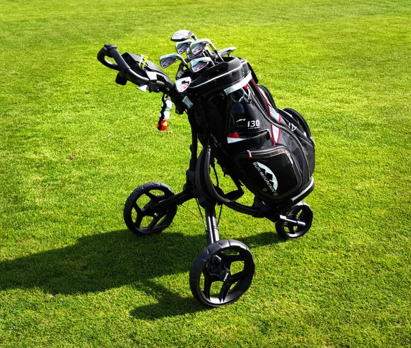 Golf bag on wheels full of golf clubs from a live golf course, golf bag on a green course, photo