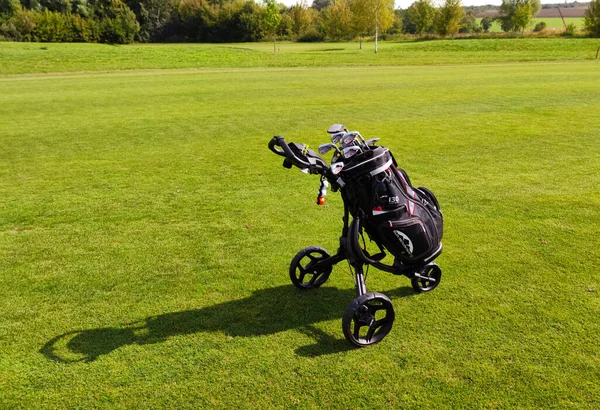 Golf bag on wheels full of golf clubs from a live golf course, golf bag on a green course. photo