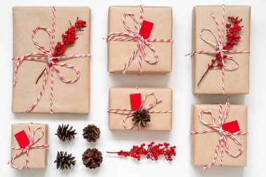 El işi kağıdında çeşitli noel hediyeleri, kırmızı böğürtlen ve beyaz arka planda çam kozalakları. Yeni yıl hediyelerinin en iyi manzarası. Düğüm konsepti. 