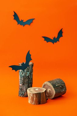 Boş ahşap podyum, turuncu arka planda kara yarasa. Doğal kozmetik reklamları için ağaç kabuklu çubuk. Cadılar Bayramı modeli. Güzellik ürünleri markalaşması için moda