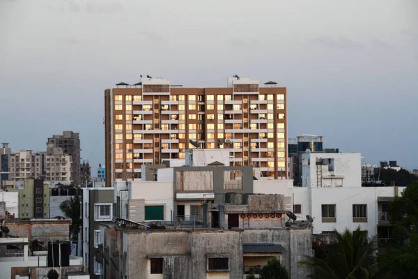 Batan güneşin ışığı bir apartmanın pencere camlarından yansıyor. Konum: Maharashtra, Hindistan Tarih: 06 Mart 2020