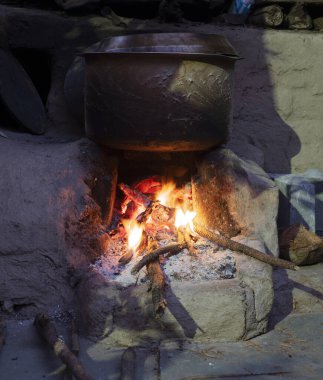 Su, odun çubuklarını yakıt olarak kullanarak toprak ocağının üzerinde kaynıyor.
