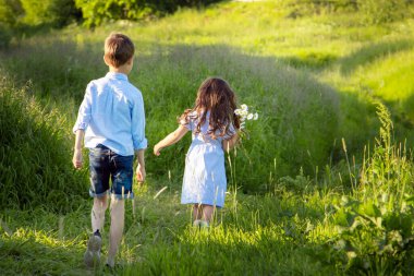 Bir erkek ve bir kız tarlada bir patika boyunca koşuyorlar. 