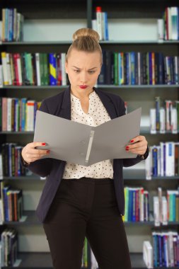 Business woman in a jacket with a folder in hands in a library clipart