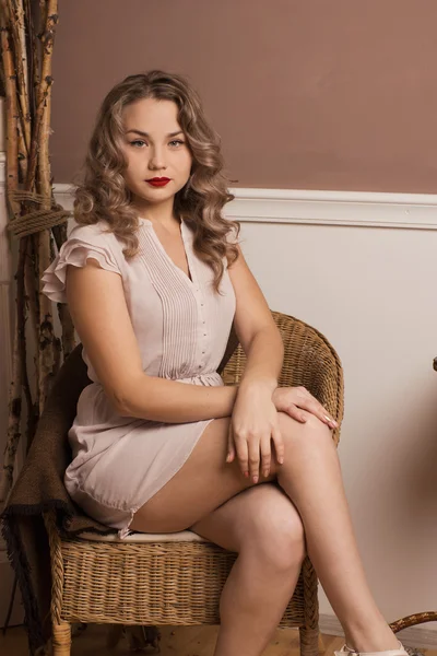 Hermosa chica sentada en una silla junto a la chimenea — Foto de Stock