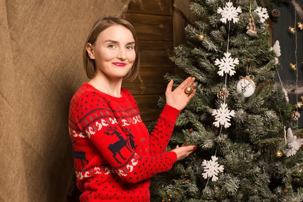 Mooi meisje in een trui ingericht kerstboom — Stockfoto