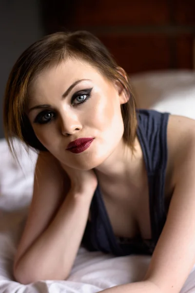 Beautiful sexy tattooed woman sitting on the bed — Stock Photo, Image