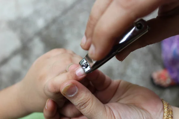 Anne, küçük oğlunun tırnaklarını tırnak makasıyla keserken.