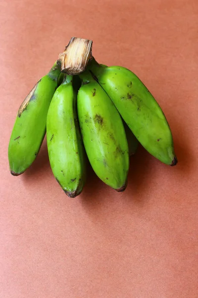 Kahverengi arka planda yeşil çiğ muz