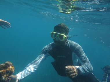 Malezya, 13 Mart 2019 - Bir adam mavi ve kristal bir suda açık denizde şnorkelle yüzüyor