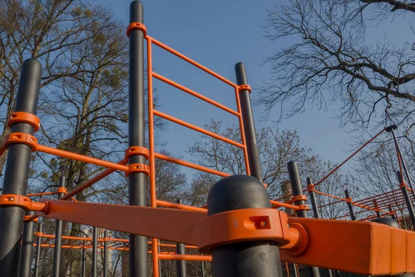 スポーツ施設 傾斜面 体操壁棒 青空と木を背景に運動場の金属と複合材料で作られた黒とオレンジの水平棒のセット — ストック写真