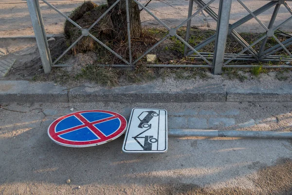 歩道の灰色の縁石と金属柵の近くの道路には レッカー車の仕事についてのプレートと車両の停止を禁止する赤と青の道路標識が落ちています — ストック写真