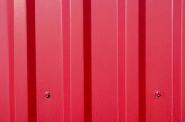 Corrugated galvanize demir tipine ait kırmızı metal bir profil parçası tabanına baskı makinası ve altıgen başlıklı çatı vidalarıyla tutturulmuş. Çitleri ve çatıları örtmek için kullanılır..