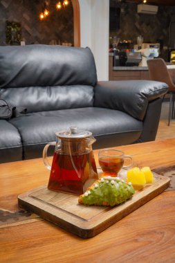 Portakal suyu ile servis edilen taze demlenmiş çay ve modern bir kafe ortamında ahşap bir masada tatlı bir pasta, rahatlatıcı yemek anları için mükemmel..