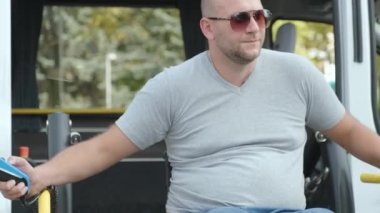 Engelliler için tekerlekli sandalyede araç kullanan bir adam. Engelliler için kaldırma ekipmanı. Tekerlekli sandalyedeki adam aracın yanında.