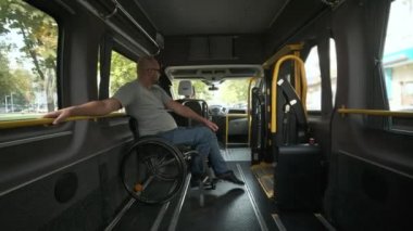 Tekerlekli sandalyedeki adam özel araçta. Engelli kişi özel bir arabayla taşınır. Özürlü insanların özel bir araçla taşınması, otobüs.
