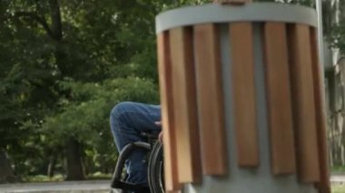 Parkta tekerlekli sandalyede yürüyen mutlu engelli adam.