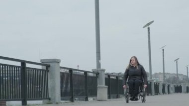 Tekerlekli sandalyedeki biri dışarıda yürüyor.