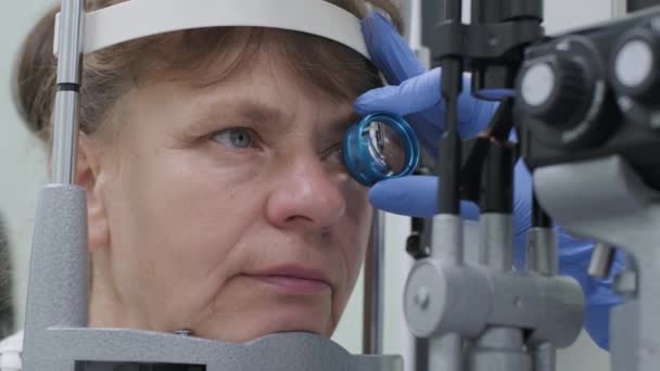 女性医師は眼科診療所の患者の目に眼科を通して見ています ビジョンの専門検査 — ストック動画