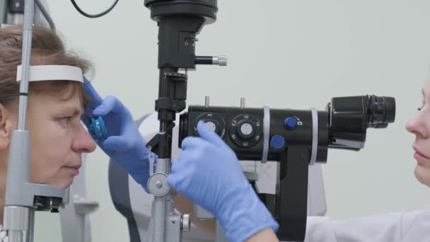 眼科诊所的女医生正在通过眼科镜检查病人的眼睛 视力的专业检查 — 图库视频影像