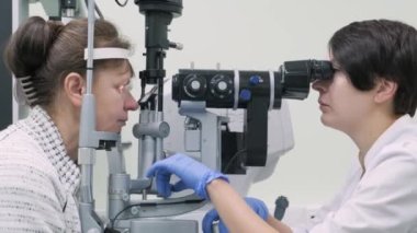 Kadın doktor göz doktorundan göz hekimliği kliniğindeki hastanın gözlerine bakıyor. Uzman vizyon denetimi