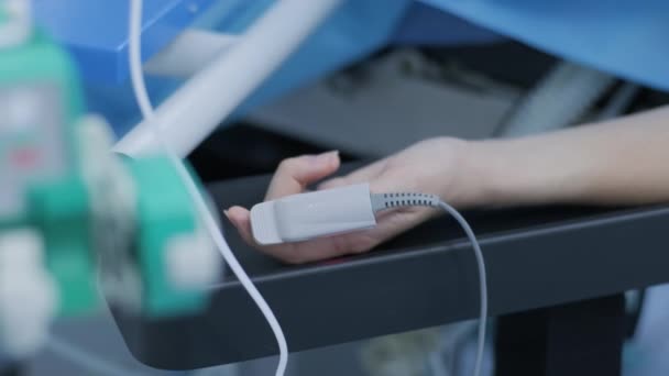 手術室にパルス酸素濃度計付きの少女の手 女性の指にパルス酸素濃度計と呼ばれる現代の医療技術 病院用具及び設備 — ストック動画