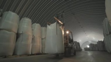 Depoda. Forklift sürücüsü depoya büyük bir çanta dolusu hammadde yığıyor..