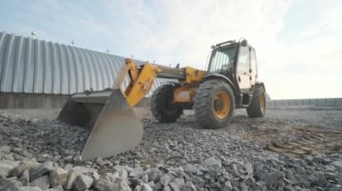 Traktör molozları kamyona taşıyor. Kazıcı-yükleyici inşaat alanındaki enkazı kazıyor ve çöp kamyonu yüklüyor. Temizleme alanı