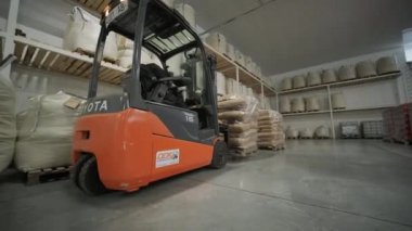 Depoda. Forklift sürücüsü depoya büyük bir çanta dolusu hammadde yığıyor..