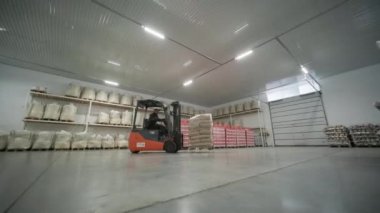 Depoda. Forklift sürücüsü depoya büyük bir çanta dolusu hammadde yığıyor..
