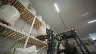 Depoda. Forklift sürücüsü depoya büyük bir çanta dolusu hammadde yığıyor..