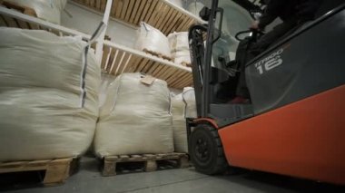 Depoda. Forklift sürücüsü depoya büyük bir çanta dolusu hammadde yığıyor..