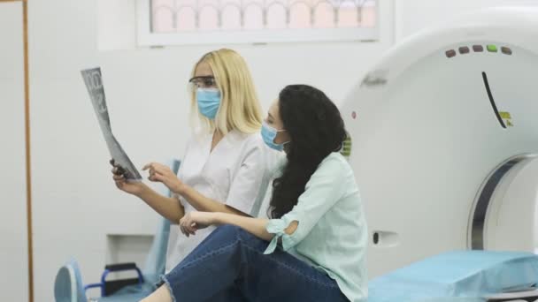 Kvinna Läkare Radiolog Förklarar Resultaten Datortomografi För Ung Kvinnlig Patient — Stockvideo