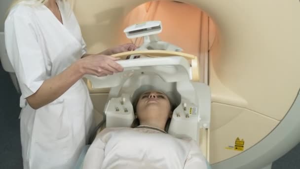 放射科医生让女病人做好脑部Mri扫描的准备 把现代化的设备 线圈放在病人的头上 — 图库视频影像