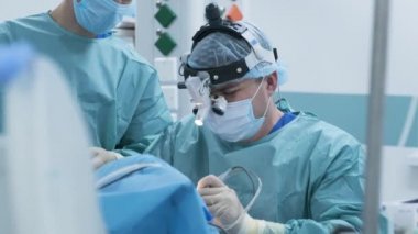 Bademcik ameliyatı, bademcik ameliyatı. Derin anestezi altında modern klinikte, en son cihazları kullanarak hasta bezleri, soğuk plazma metodunu, boğazdaki şişliği, doktor yeni bir sondayla, tıbbi farla, cerrahi hoparlörlerle çalışır.