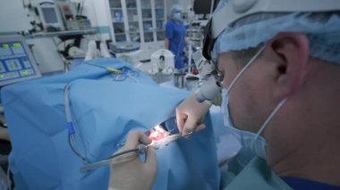 Bademcikleri derin anestezi altında çıkarma operasyonu, cerrah en son cihazları kullanır, soğuk plazma yöntemi, boğazda şişme, doktor yeni bir sonda, tıbbi far, cerrahi lenslerle çalışır.