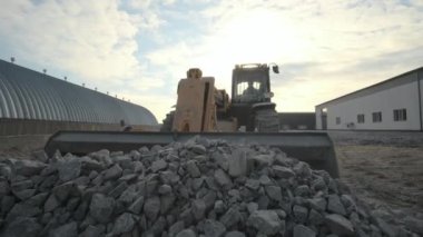 Traktör molozları kamyona taşıyor. Kazıcı-yükleyici inşaat alanındaki enkazı kazıyor ve çöp kamyonu yüklüyor. Temizleme alanı