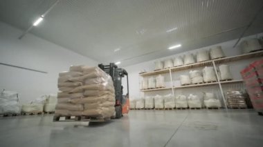 Depoda. Forklift sürücüsü depoya büyük bir çanta dolusu hammadde yığıyor..