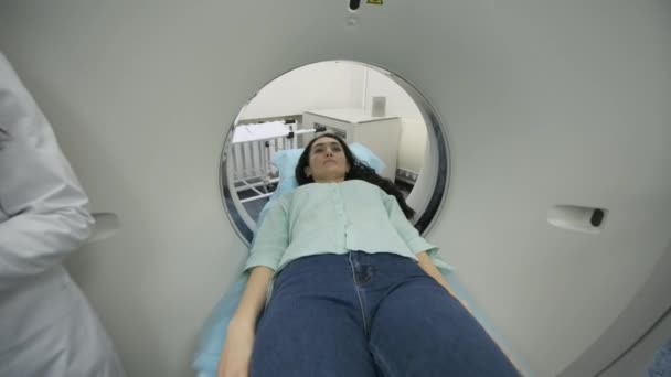 Paciente do sexo feminino é submetida a tomografia computadorizada ou ressonância magnética sob supervisão de dois radiologistas qualificados na clínica médica moderna. Paciente deitado em uma mesa de TC ou RM — Vídeo de Stock