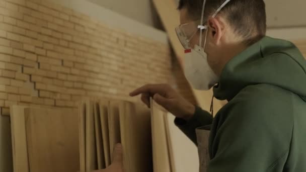 Ξυλουργός επαγγελματίας σε μάσκα και γυαλιά ελέγχει το ξύλο ακατέργαστο, κόντρα πλακέ πάνελ — Αρχείο Βίντεο