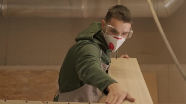 Ξυλουργός επαγγελματίας σε μάσκα και γυαλιά ελέγχει το ξύλο ακατέργαστο, ξύλινη σανίδα, κόντρα πλακέ πίνακα — Αρχείο Βίντεο