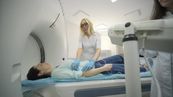 "Due radiologi inseriscono un catetere endovenoso per iniettare contrasto con la paziente donna sottoposta a TAC o risonanza magnetica. Paziente sdraiato su un letto di scansione TAC o RM — Video Stock