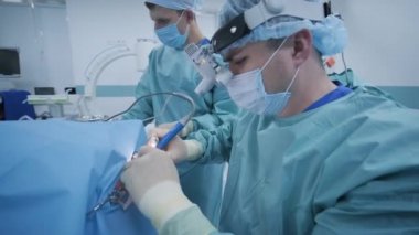 Bademcikleri derin anestezi altında çıkarma operasyonu, cerrah en son cihazları kullanır, soğuk plazma yöntemi, boğazda şişme, doktor yeni bir sonda, tıbbi far, cerrahi lenslerle çalışır.