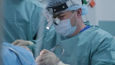 Operation of removing tonsils. tonsillectomy under deep anesthesia, using latest devices, cold plasma method, cuts swelling in throat, doctor works with new probe, medical headlamp, surgical loupes