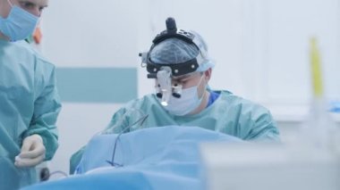 Bademcikleri derin anestezi altında çıkarma operasyonu, cerrah en son cihazları kullanır, soğuk plazma yöntemi, boğazda şişme, doktor yeni bir sonda, tıbbi far, cerrahi lenslerle çalışır.