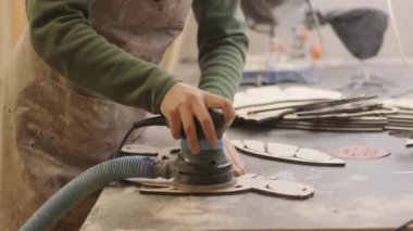 Bir marangoz öğütücüyle lazer makinesinden yapılmış bir tahta parçasını öğütür.