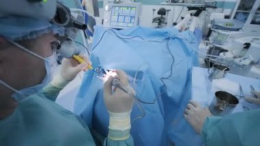 Operation of removing tonsils. tonsillectomy under deep anesthesia, using latest devices, cold plasma method, cuts swelling in throat, doctor works with new probe, medical headlamp, surgical loupes